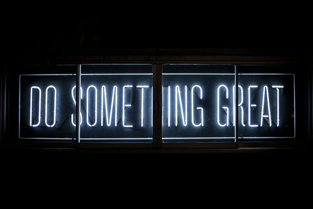 Photo of a neon sight stateing to "do something great" . Encouragement for a ux portfolio design